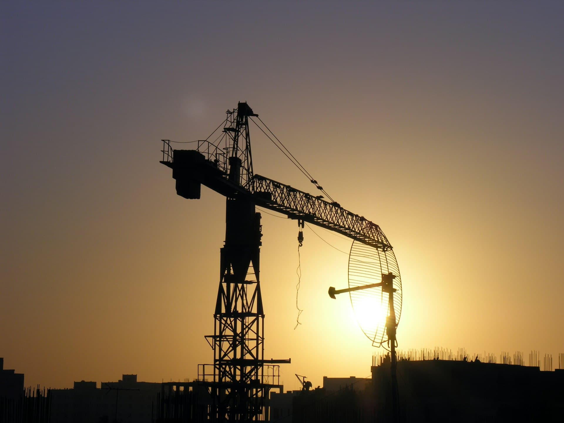 A construction crane silhouetted against the sunset